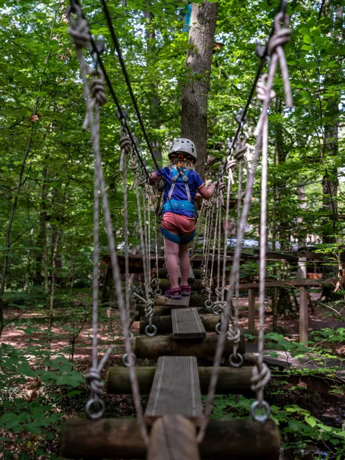 Mädchen balanciert im Kletterpark über Baumstämme