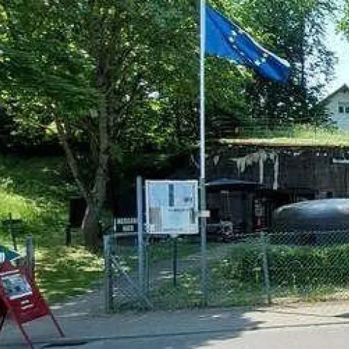 Ein ehemaliges Bunkergebäude mit einem EU-Flagge im Vordergrund. Daneben befindet sich ein Schild für das Westwallmuseum.
