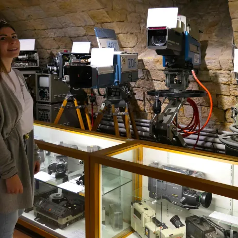 Eine junge Frau betrachtet sich interessiert historische Filmvorführtechnik.