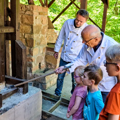 Eine Familie besucht die Bergbauerlebniswelt in Imsbach. Die Kinder schauen gespannt dem Gästeführer zu.