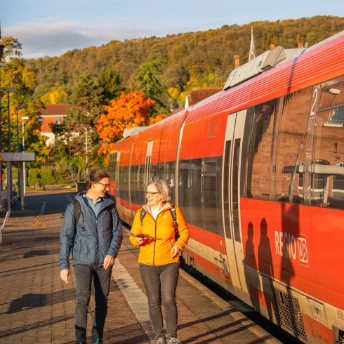 Zwei Personen in Wandbekleidung laufen an einem Bahnsteig 